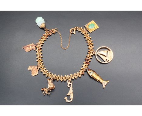 A gold charm bracelet, comprising a fancy link chain marked "14K" bearing eight charms, three being nine carat gold charms, f