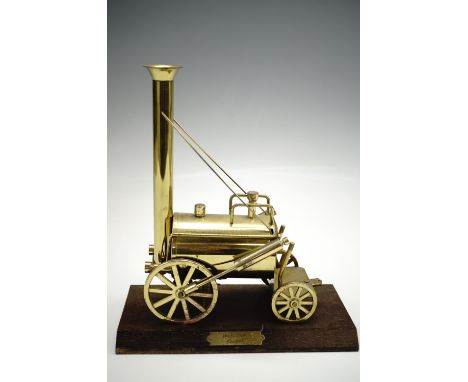 A brass scale model of Stephenson's "Rocket" railway locomotive, mounted on a bevelled wooden base with a brass name plaque, 