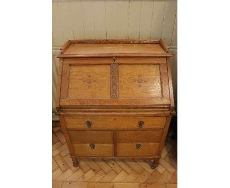 An Arts and Crafts influenced fall front bureau, constructed from light oak and having a gallery top, the fall front decorate