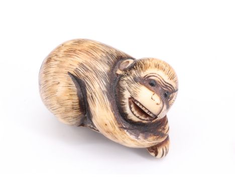 A Japanese stag horn netsuke of a crouching monkey with inlaid eyes, 3.5 cm