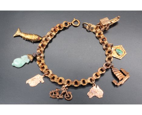 A gold charm bracelet, comprising an unmarked high carat yellow fancy link bracelet bearing eight charms, five being nine car