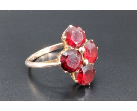 A vintage garnet and yellow metal finger ring, comprising four circular facet-cut stones each of approximately 7 mm set in a 