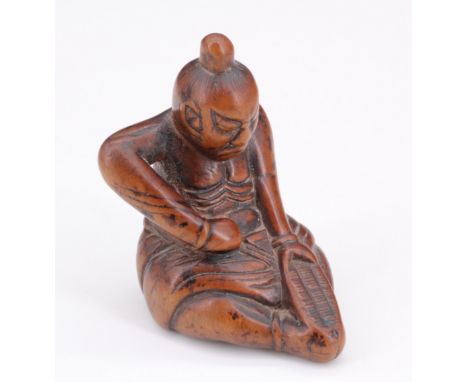 A Japanese carved wood netsuke of a seated Nio repairing a sandal, 4 cm 