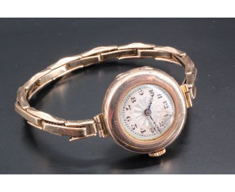 A lady's 9 ct gold wristwatch, on an expanding gold filled bracelet, the dial being engine turned, with Arabic numerals and b