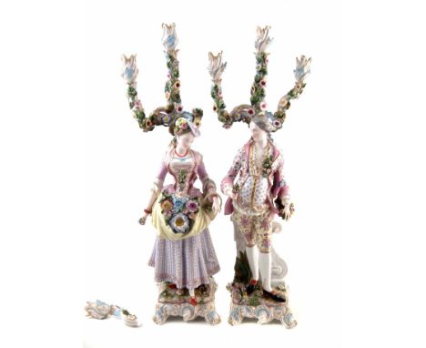 Pair of large continental porcelain table candelabra, modelled as a lady and gentleman collecting flowers, stood on scrolled 