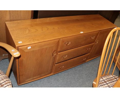 An Ercol light elm side board, the bank of three drawers, flanked by a pair of covered drawers 69cm by 155cm by 43cm (en suit