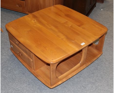 An Ercol light elm coffee table, fitted with drawers and recesses, moving on castors, 40cm by 80cm square 