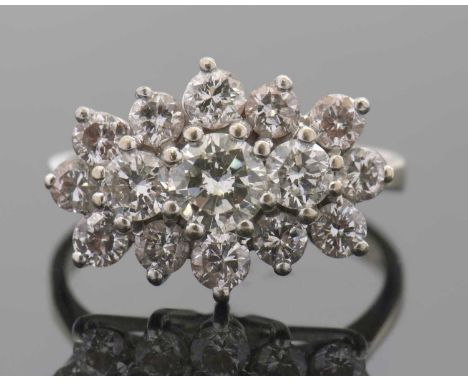 An 18ct diamond cluster ring, set to centre with three graduated round brilliant cut diamonds and surrounded by smaller round