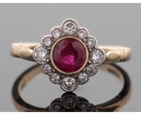An 18ct ruby and diamond ring, the round ruby in rubover mount and surrounded by round brilliant cut diamonds, head overall 1