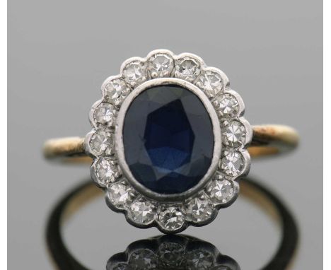 An 18ct and platinum sapphire and diamond ring, the oval collet mounted sapphire surrounded by single cut diamonds, total est