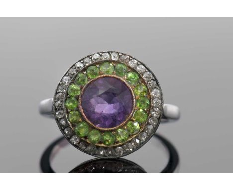 An early 20th century gemset ring, in Suffragette colours, the central round amethyst surrounded by small round demantoid gar