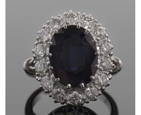 A sapphire and diamond cluster ring, the oval deep blue sapphire surrounded by round brilliant cut diamonds, total estimated 