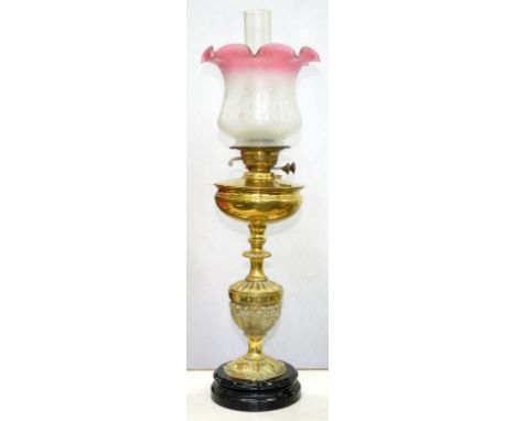 A LATE VICTORIAN EMBOSSED SHIELD SHAPED OIL LAMP WITH COMPRESSED FOUNT AND BURNER ON BLACK GLAZED POTTERY FOOT WITH AN ETCHED