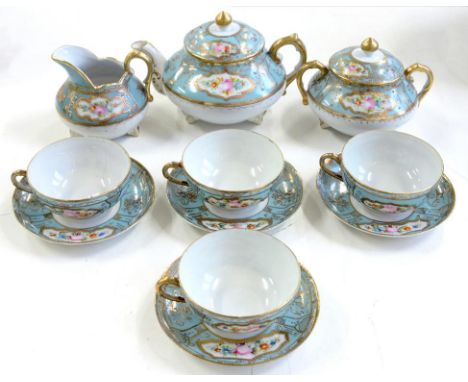 A JAPANESE PORCELAIN TEA SERVICE, PAINTED WITH PANELS OF FLOWERS ON A PALE BLUE AND RAISED GILT DECORATED GROUND, TEAPOT AND 