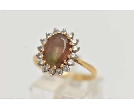 AN 18CT GOLD SMOKY QUARTZ AND DIAMOND CLUSTER RING, the oval smoky quartz within a brilliant cut diamond surround, all in cla