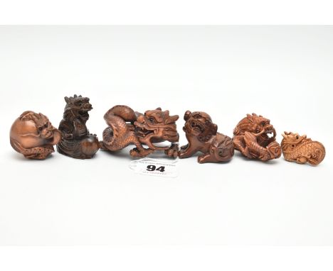 FOUR 20TH CENTURY CARVED TREEN NETSUKE AND TWO OKIMONO, all in the form of dragons, all with inset eyes, one inset with mothe