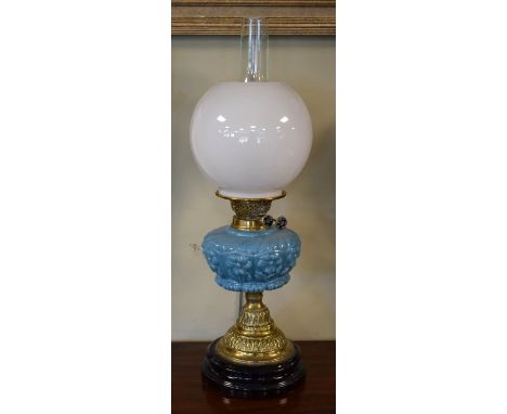 Victorian oil lamp, the blue glass reservoir having foliate decoration in relief, embossed brass column and standing on a bla