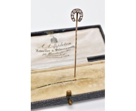 AN EDWARDIAN DIAMOND STICK PIN, the yellow metal pin in the form of a horse shoe, set with five old cut diamonds and four ros