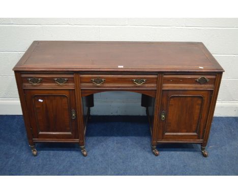 AN EDWARDIAN MAHOGANY KNEE HOLE DESK, with three various drawers above panelled cupboard doors, on ceramic casters, width 136