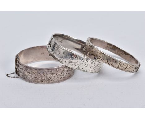 THREE SILVER HINGED BANGLES, the first a wide bangle with a foliate engrave design, push pin clasp and additional safety chai