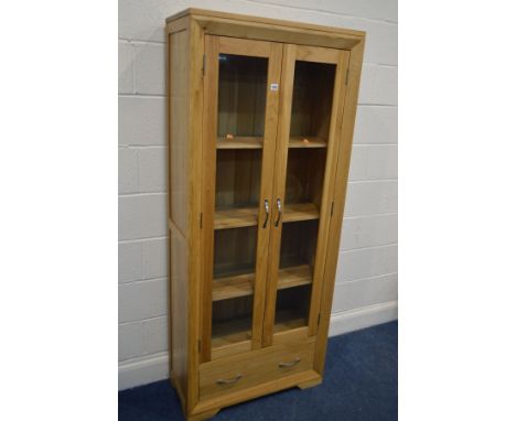 A MODERN SOLID LIGHT OAK GLAZED DOUBLE DOOR BOOKCASE, with three adjustable shelves, above a single drawer, width 78.5cm x de