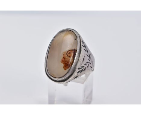 A WHITE METAL GEM SET RING, of oval design set with a cabochon cloudy stone assessed as agate, within a collet mount, feather