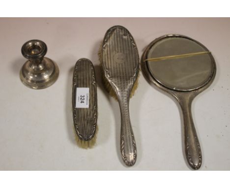 A HALLMARKED SILVER THREE PIECE BRUSH AND MIRROR SET A/F TOGETHER WITH A HALLMARKED SILVER CANDLESTICK (4)