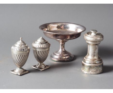 A silver pepper grinder, a pair of silver pepper pots and a pedestal nut dish with weighted base