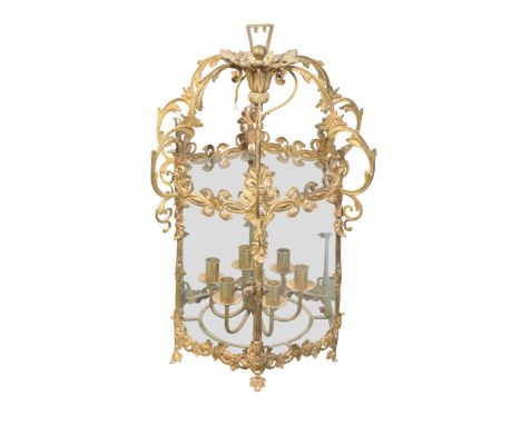 A GILT METAL AND BRASS HALL LANTERN hexagonal with glazed panelling, the foliate cast corona and frame supporting a six light