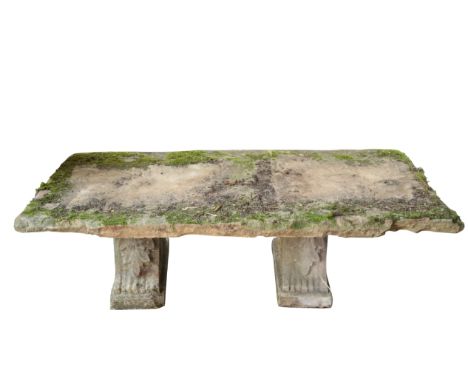 A STONE GARDEN BENCH the weathered rectangular top on two scrolling acanthus supports, 41cm high x 134cm wide x 63cm deep