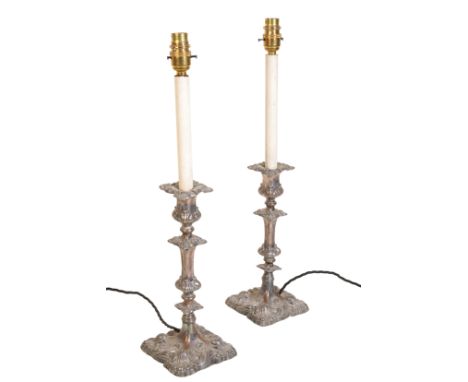 A PAIR OF SILVER PLATED CANDLESTICK TABLE LAMPS in Rococo style, the fitments issuing from foliate sconces, the candlesticks 