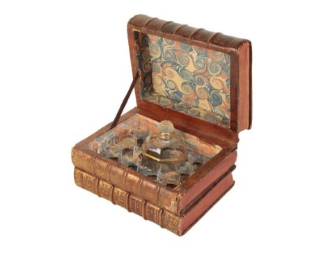 AN EDWARDIAN DRINKS CADDY IN THE FORM OF LEATHER BOUND BOOKS containing glass decanter and shot glasses, 15cm high x 25cm wid