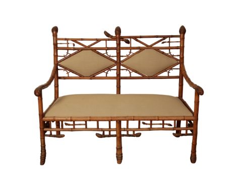 A CARVED BAMBOO BENCH with padded lozenge panels to the back, sprung padded seat, covered in fawn cotton, 106cm high x 128cm 