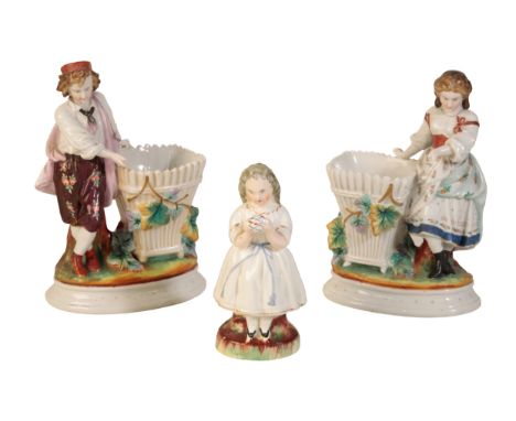 A STAFFORDSHIRE FIGURE OF A YOUNG GIRL holding a ball, together with a pair of ceramic figures, standing next to a vacant bas