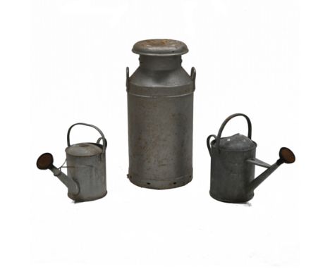 An galvanised milk churn with lid, "United Dairies", 74cm high, 35cm diameter, along with two galvanised watering cans, 2 gal