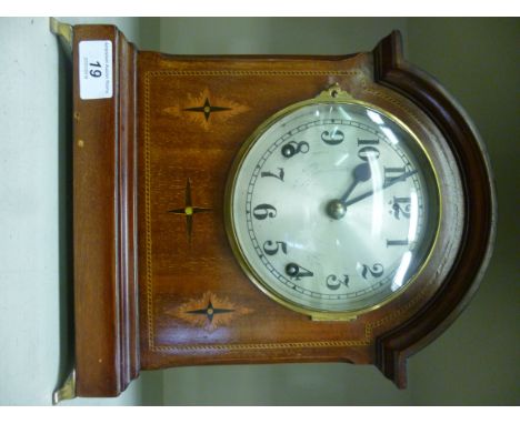 An Edwardian mahogany cased bracket clock with marquetry ornament, having an arched top, over straight sides, on lacquered br