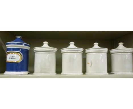 An early 20thC blue and white china, chemists' cylindrical jar and cover; and a set of four similar, cream coloured jars, ins