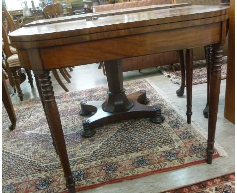 An early 19thC mahogany card table, the D-shaped foldover top enclosing a green baise lined interior, raised on ring turned, 