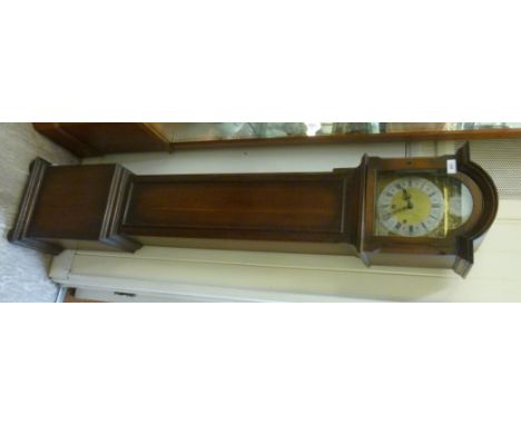 A 20thC oak cased grand-daughter clock, having a round arched hood, over a straight trunk with a pendulum door, on a box base