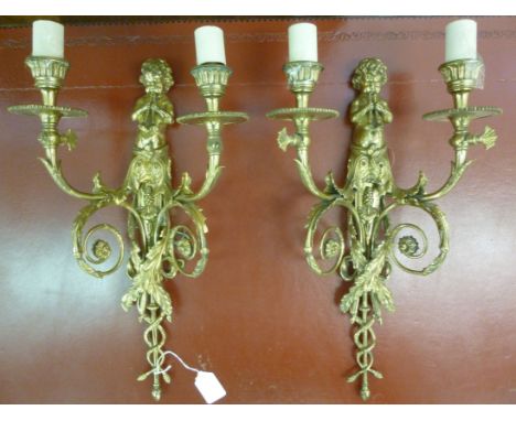 A pair of 19thC design lacquered cast brass appliques, each featuring a trumpeting cherubic figure and twin, foliate scrolled