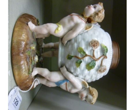 A late 19thC Continental porcelain oil lamp base, the spherical reservoir supported by three cherubic figures, on a naturalis