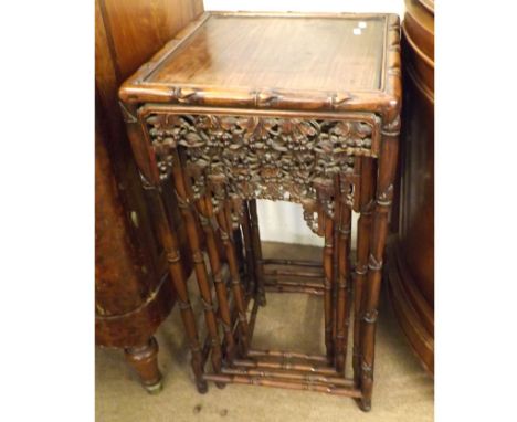 A nest of four Oriental hardwood tables of square form decorated with pierced foliate rims, raised on bamboo-effect legs and 