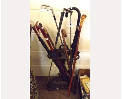 An Antique Cast Iron Stick Stand with removable base tray containing an assortment of various umbrellas, golf clubs and walki