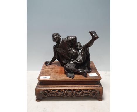 A Chinese bronze Sculpture of a man in robes falling over, on associated hardwood Stand 6 1/2in H 
