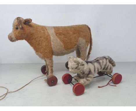 A vintage Steiff pull along Cow with button in ear (some wear to horns and tail) 10in H, and a pull along Cat 