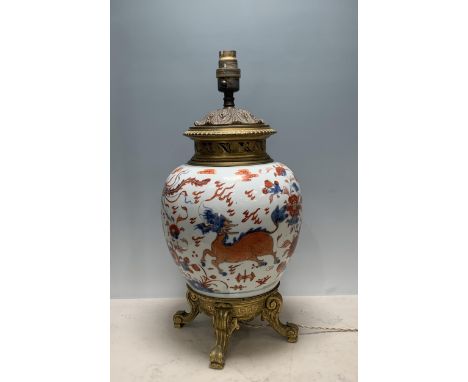 A Chinese porcelain and gilt metal Table Lamp with design of dragons and flowers and raised on four scrolled supports, 18in H