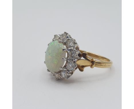 An Opal and Diamond Cluster Ring claw-set oval opal cabochon within frame of ten brilliant-cut diamonds, ring size T, approx 