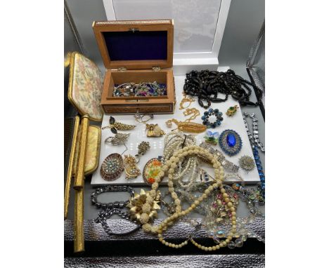 A Vintage red case containing a large quantity of vintage jewellery which includes necklaces, brooches and dressing table set