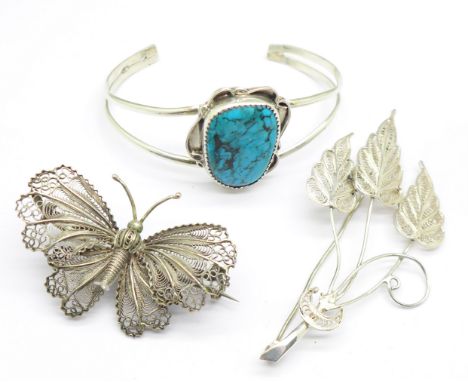 A silver and turquoise mounted bangle and two filigree brooches including a butterfly 