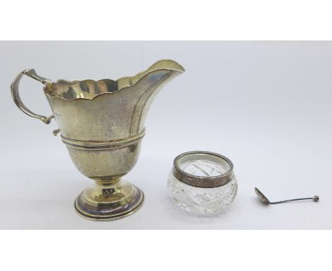 A silver helmet shaped cream jug, hallmarks rubbed, 83g, 9.5cm, and a silver rimmed glass salt and spoon 